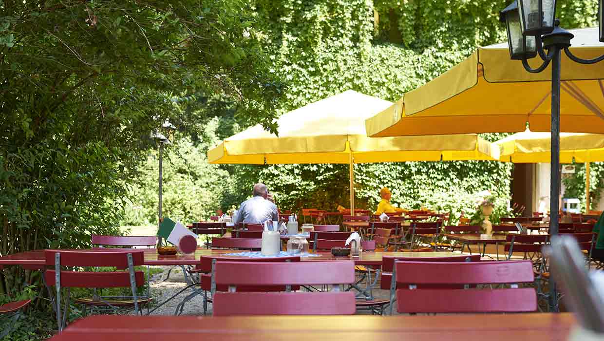 Biergarten mit gelben Sonnenschirmen und roten Stühlen
